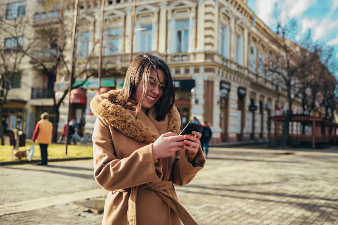 Mulher que estudar em uma das melhores universidades do mundo olhando para o celular no campus