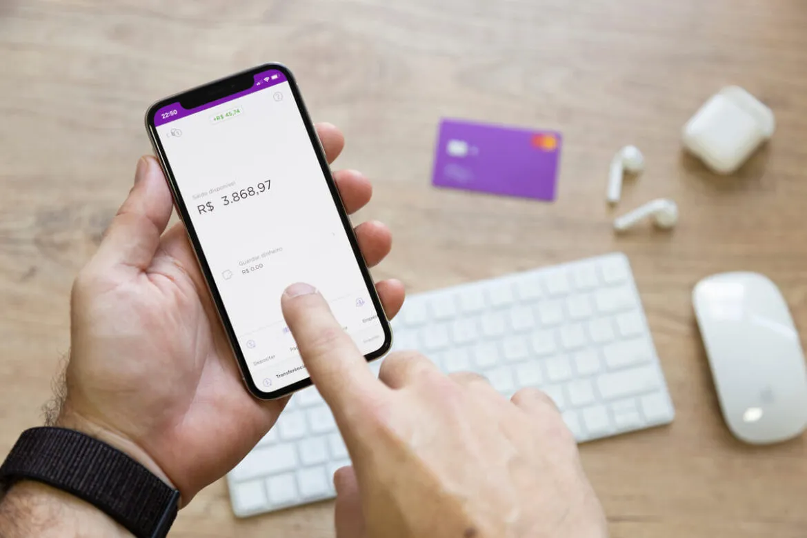 Pessoa segurando o celular aberto no aplicativo no Nubank para saber como pagar contas no exterior pelo Nubank