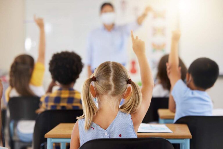 Crianças respondendo as perguntas do professor na sala de aula.