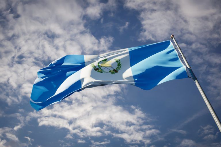 Curiosidades sobre a Guatemala: bandeira do estado nacional da Guatemala tremulando ao fundo do céu