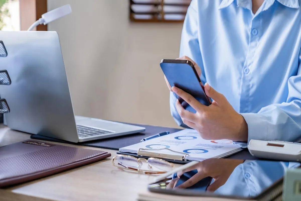 Mãos segurando um smartphone no escritório