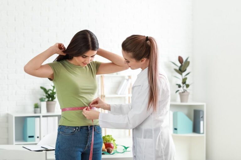 Nutricionista atendendo uma paciente mulher e pegando as medidas da cintura dela