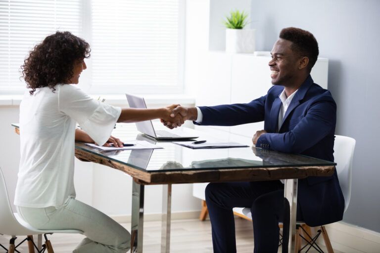 Duas pessoas firmando um contrato com aperto de mãos.