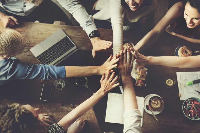 Pessoas praticando a cultura colaborativa sentados em uma mesa de uma startup.