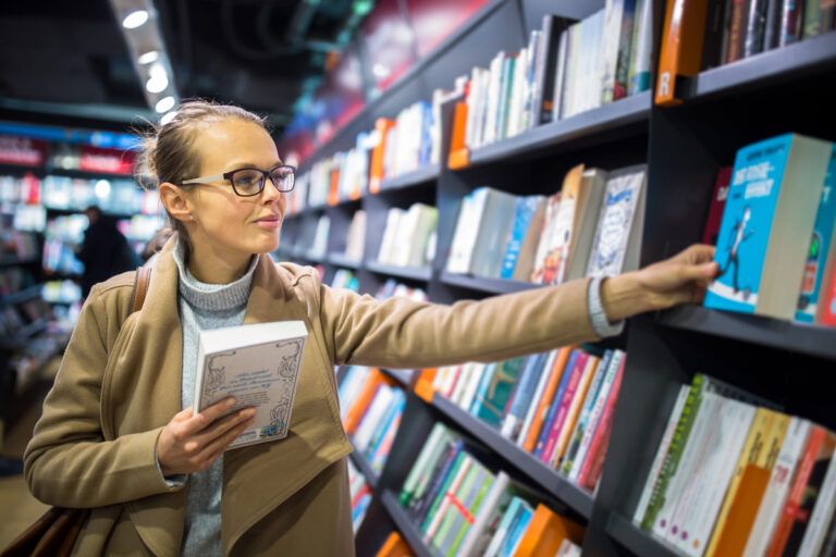 Mulher escolhendo livros para empreendedores em uma biblioteca.