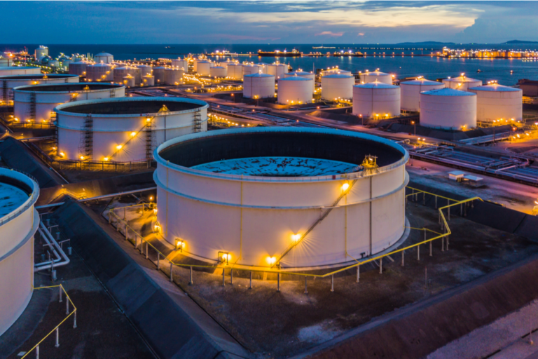 Foto de barris de petróleo em fim de tarde com luzes acesas