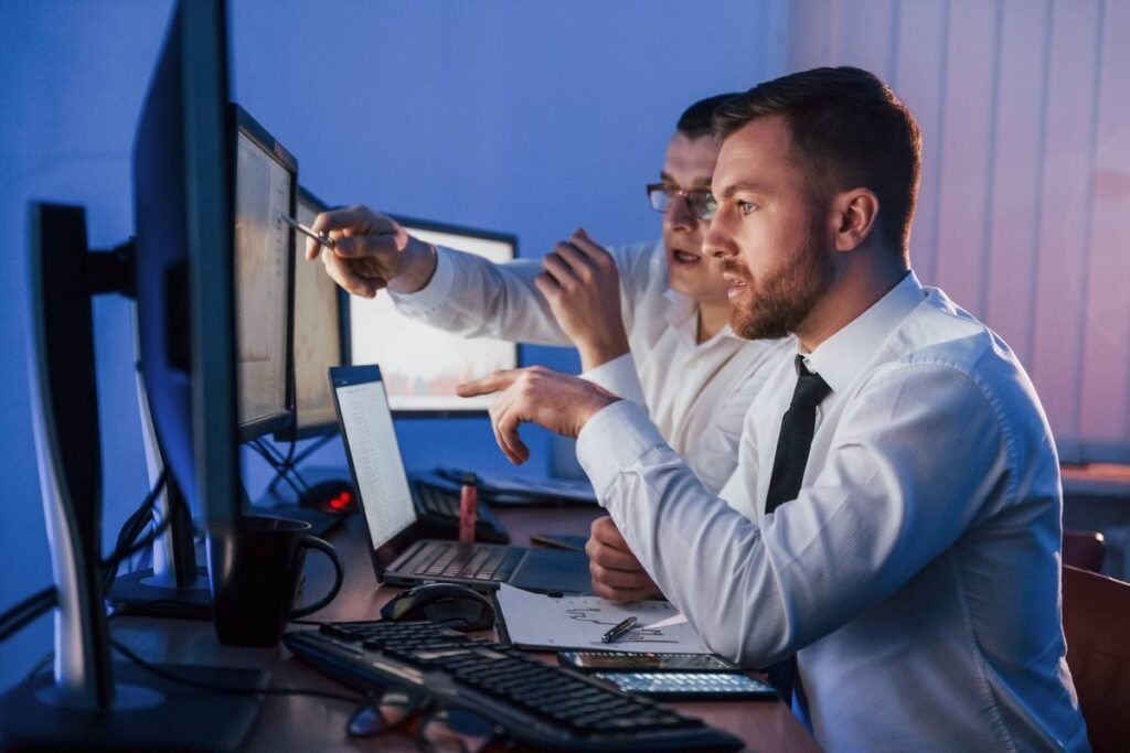 Dois homens analisando o histórico das Units no computador. 