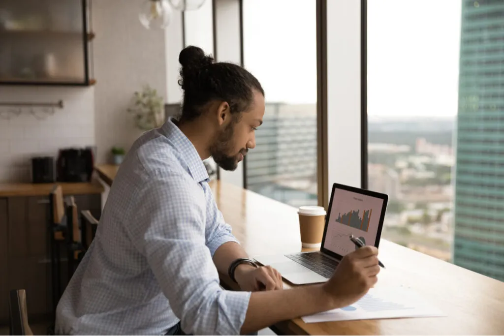 homem analisando e estudando no computador o valor mínimo para investir em criptomoedas