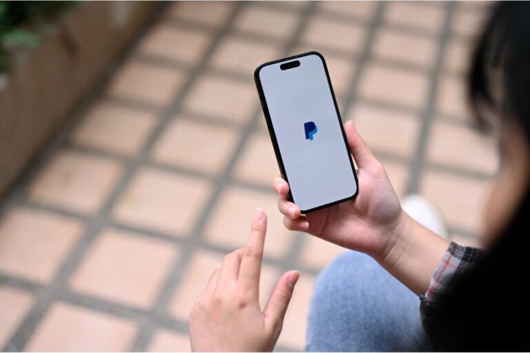 Pessoa olhando no celular como enviar dinheiro para o exterior pelo PayPal.