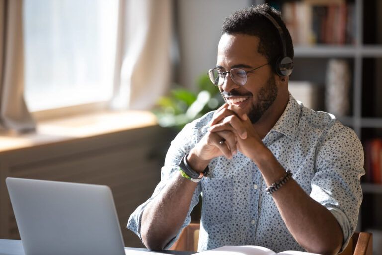 Homem de óculos olhando sorridente para o computador, simulando customer success.