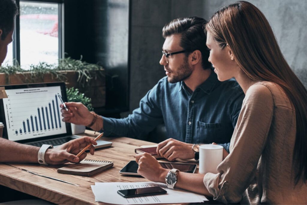 Equipe de três pessoas fazendo análise de um gráfico no computador