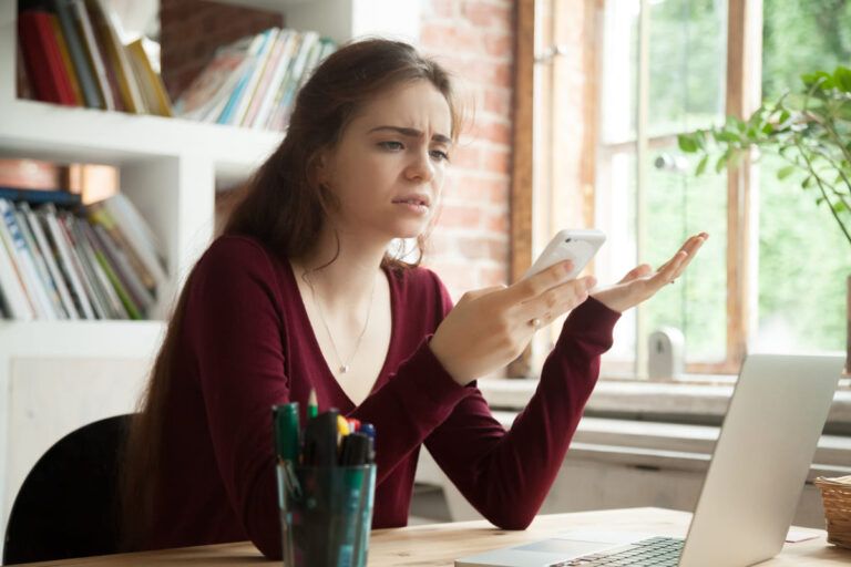 Imagem de mulher segurando o celular para falar que a Vivo está fora do ar.