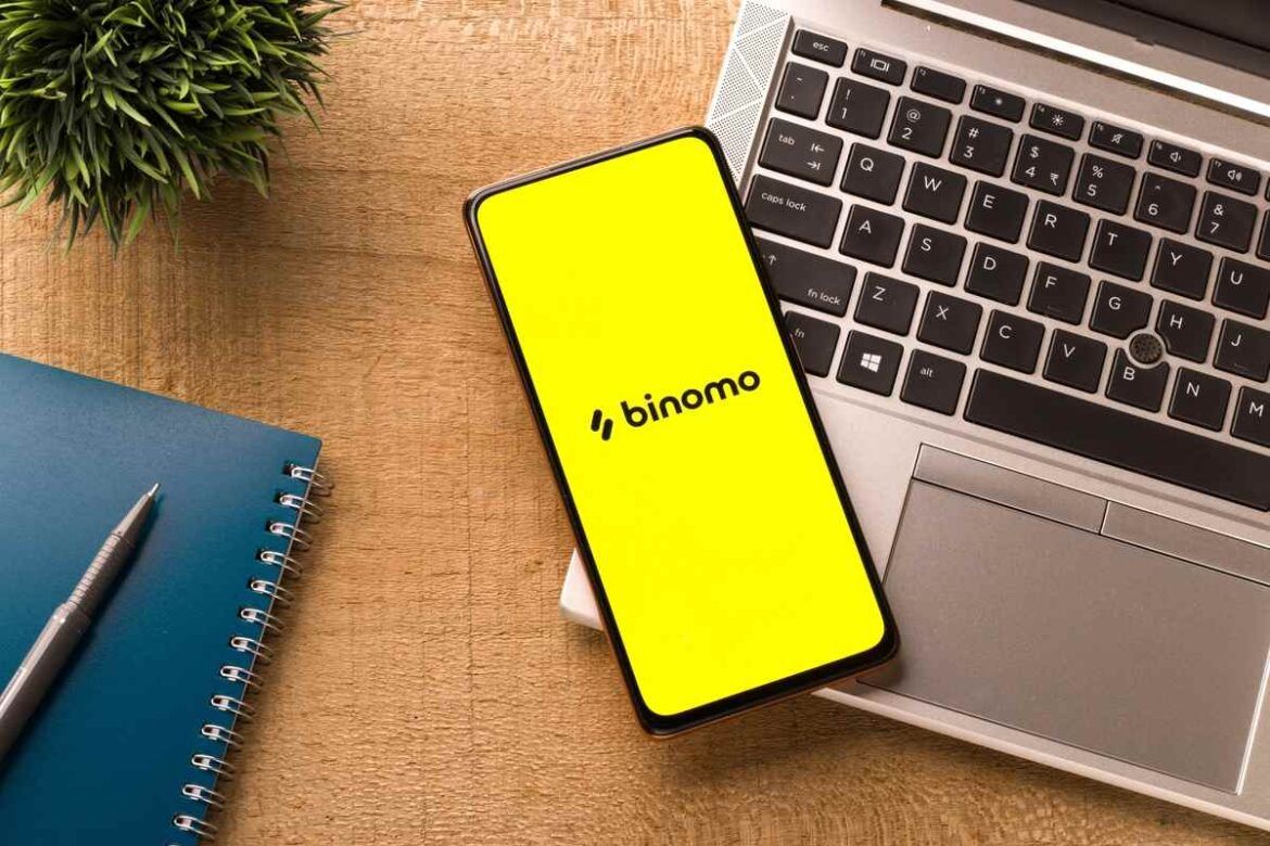 Smartphone com o logo da Binomo próximo do notebook