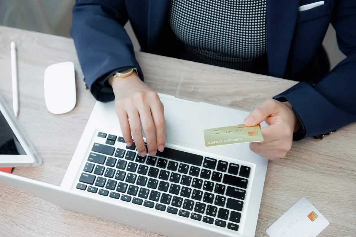 Mãos de homem com cartão de crédito e notebook na frente