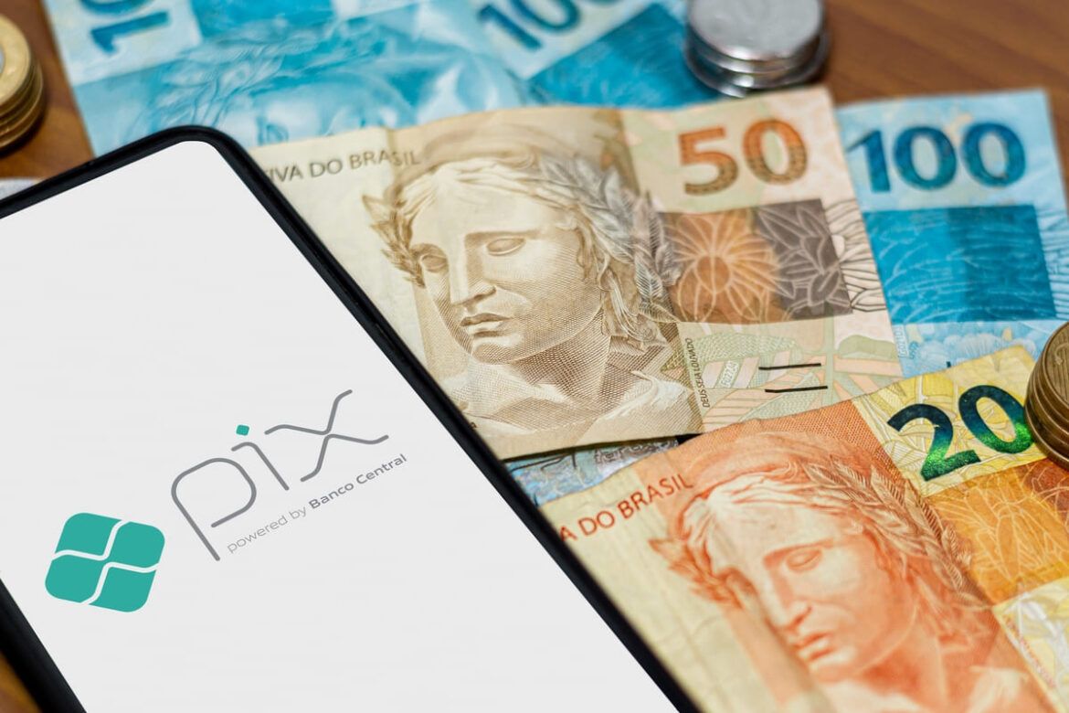 Dinheiro fisico e celular exibindo o serviço Pix, que agora ficará mais seguro com novas medidas do Banco Central