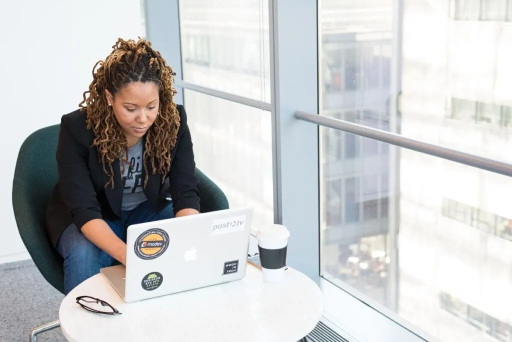 Uma mulher preta, em um ambiente empresarial, experimentando as atividades da rotina do social media.