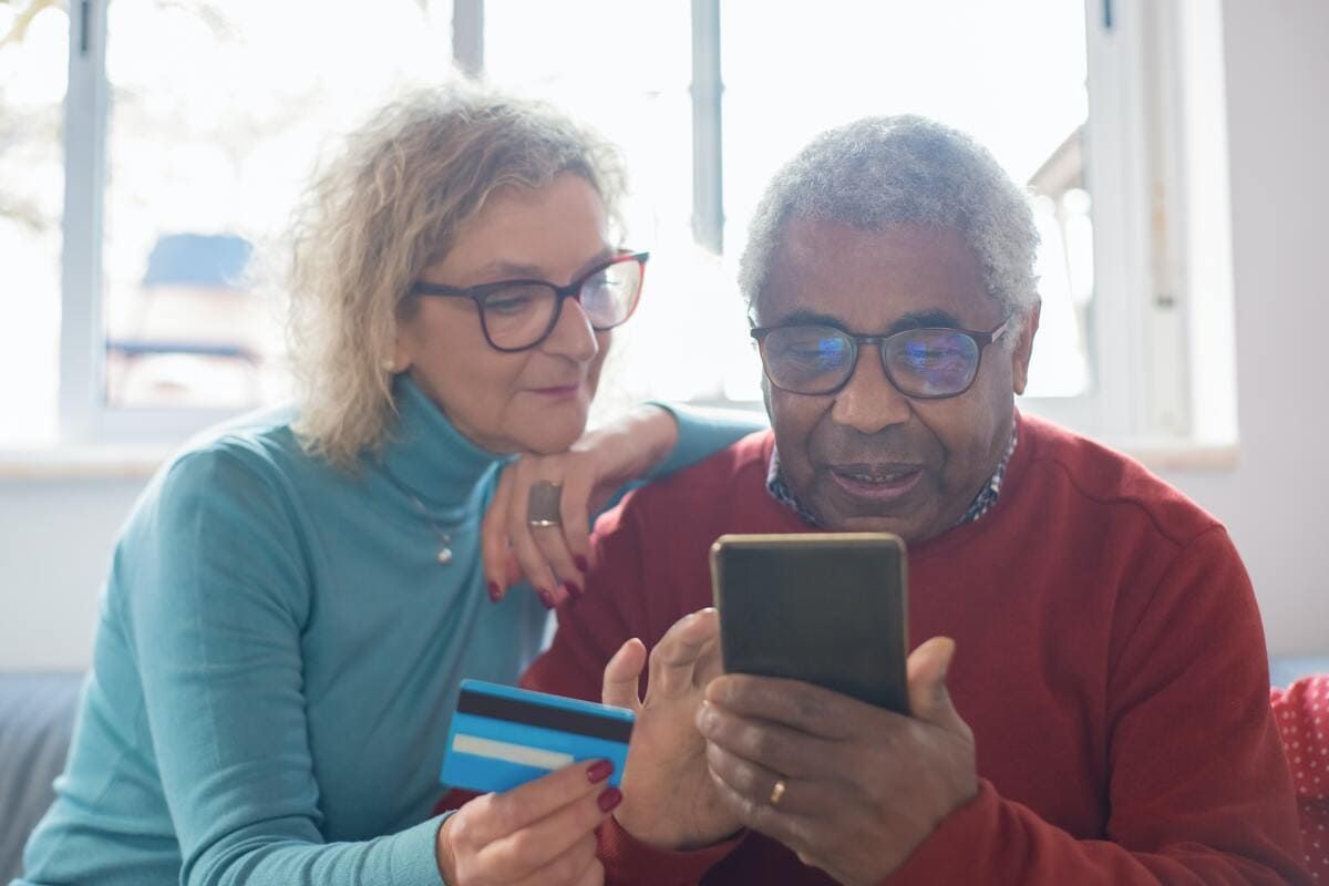 Casal olhando o telefone acessando a Amazon para comprar com o cartão Amazon