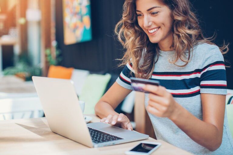 Mulher com cartão de crédito na mão fazendo compras online