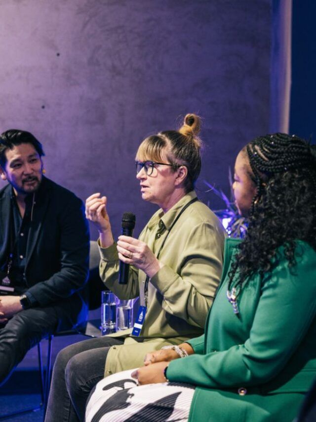 Palestrantes discursando em um painel no evento