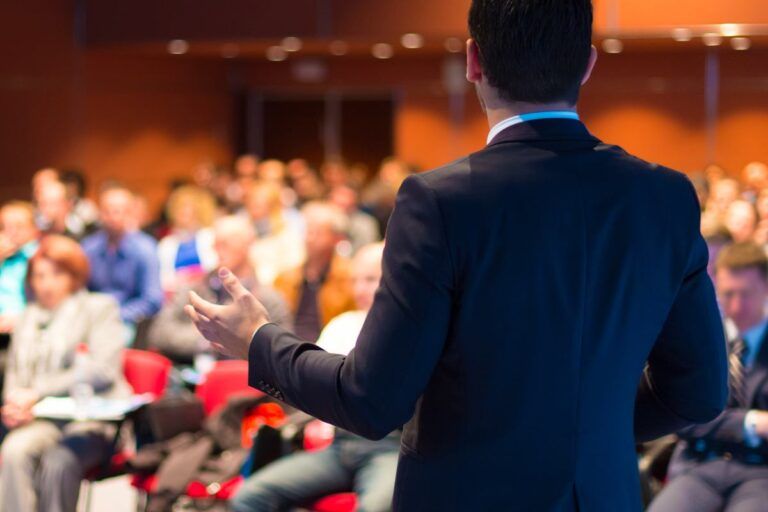 Palestrante durante evento em uma sala de conferência.