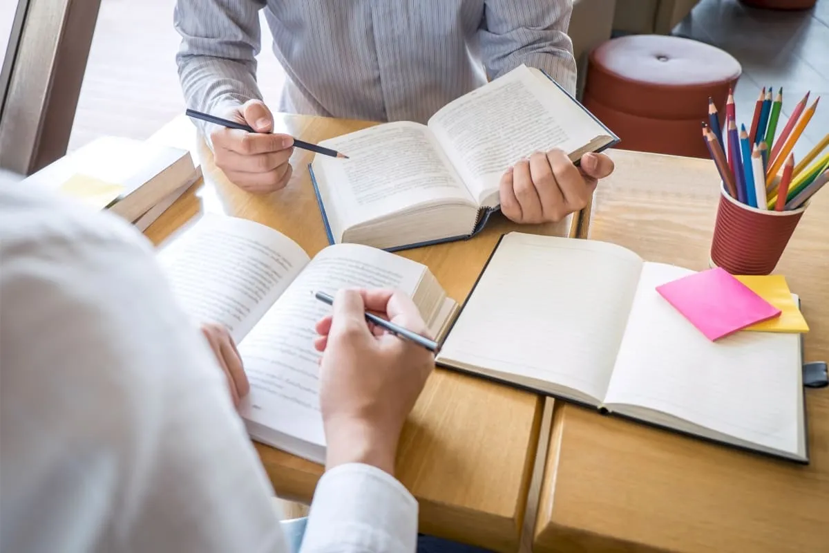 Pessoas usando livros para saber como aprender italiano.