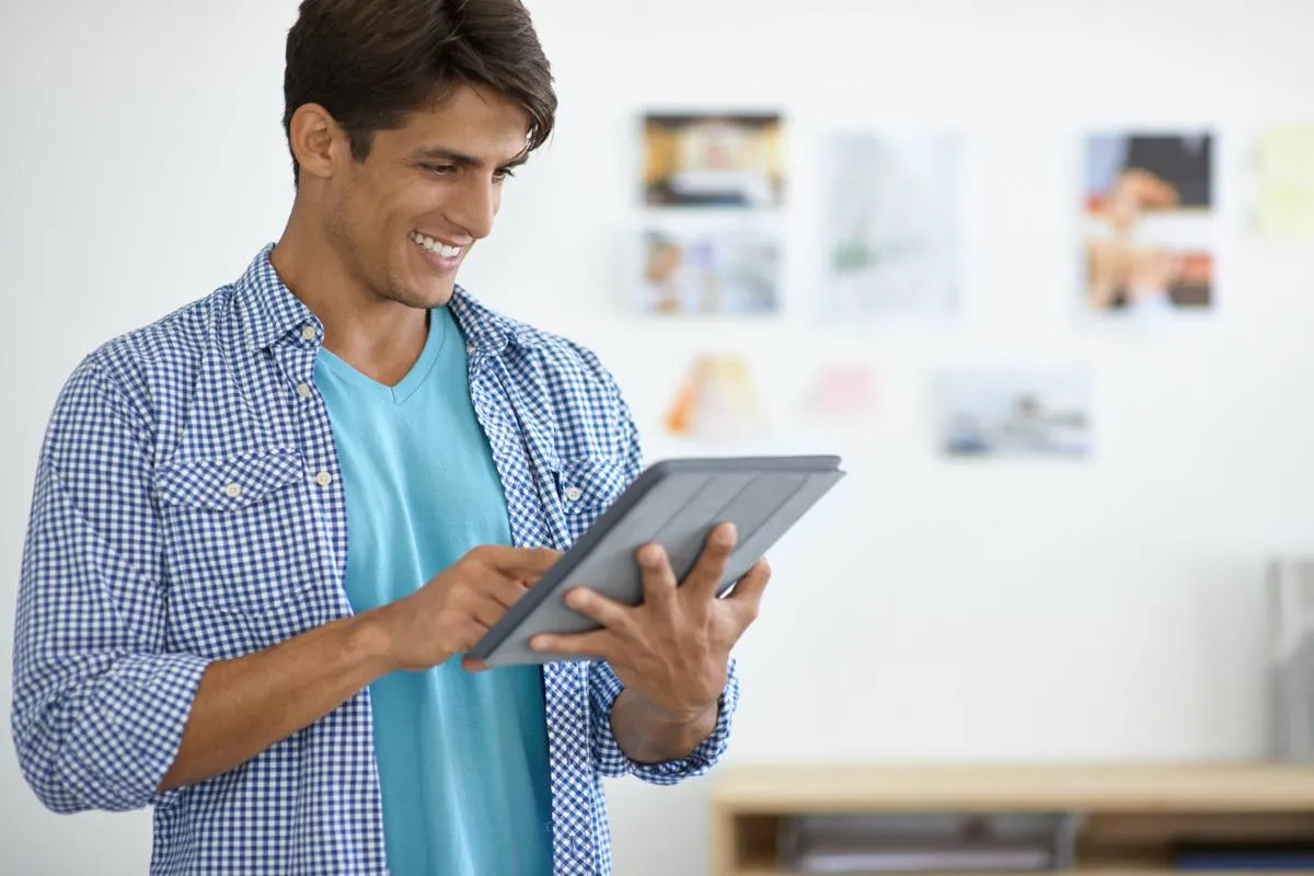 Homem feliz acessando site do Webflow pelo tablet.