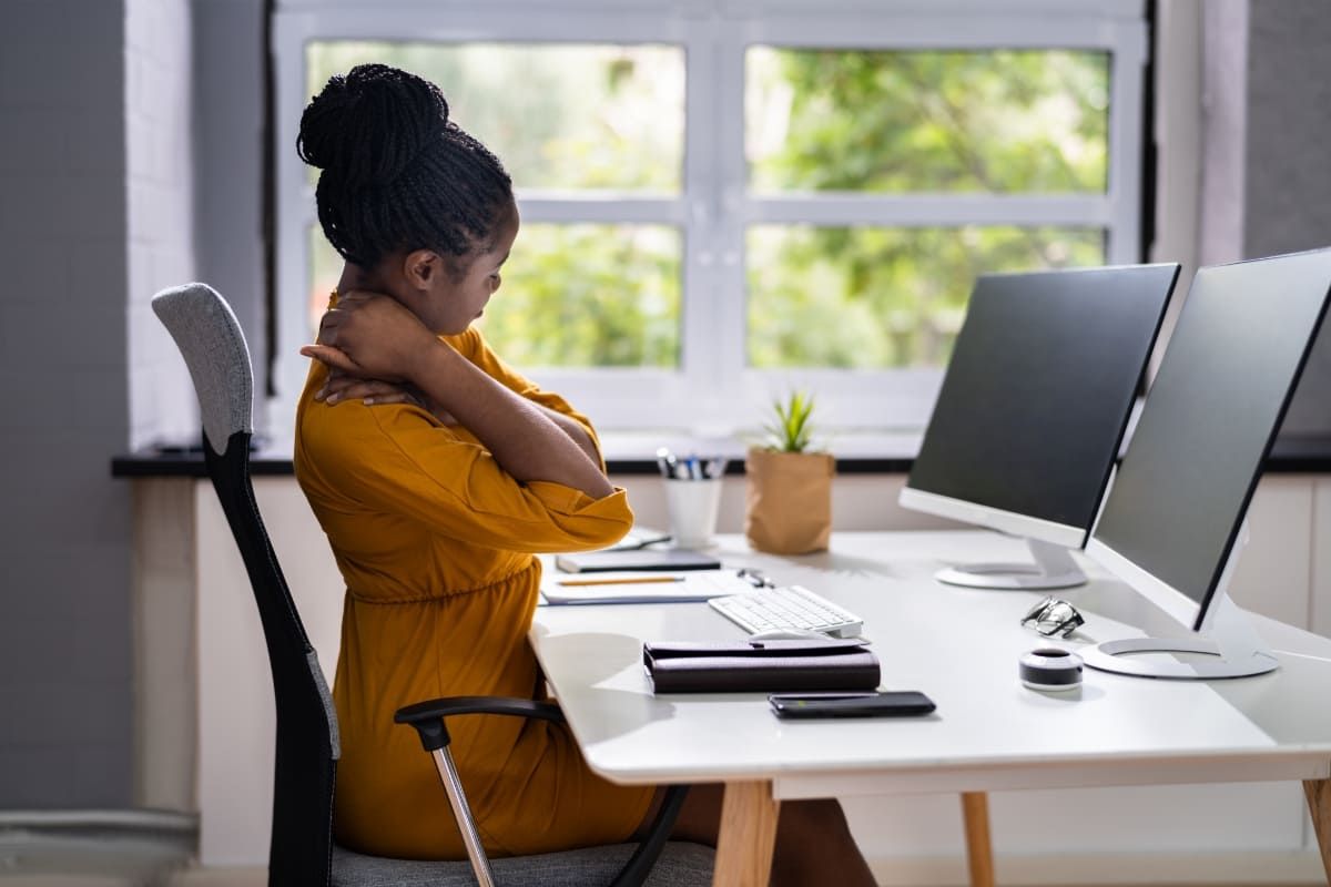 Mulher com problemas de ergonomia no trabalho.