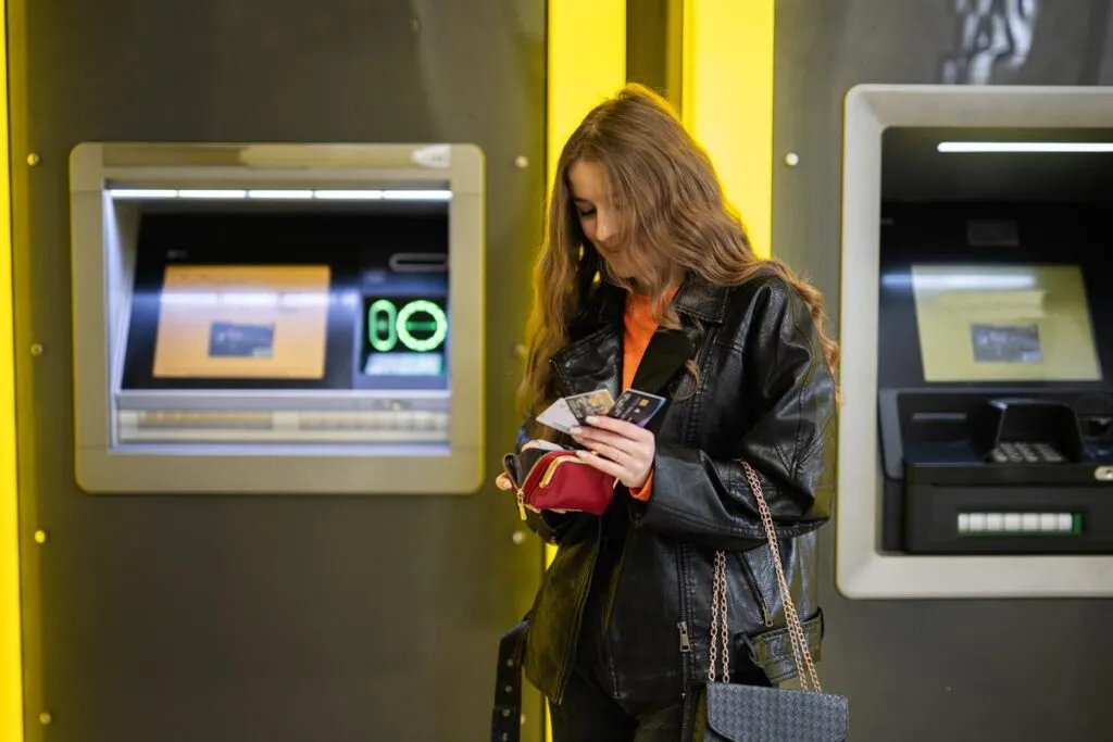 Mulher guardando cartões após sacar dinheiro em Portugal.