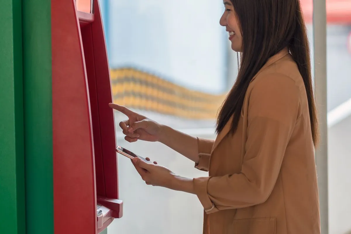 Mulher feliz sacando dinheiro no Japão no caixa eletrônico.