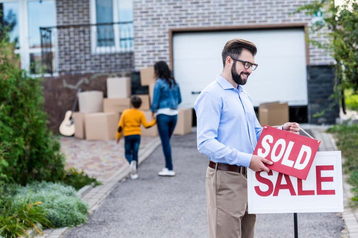 Homem retirando placa após comprar casa em Toronto.