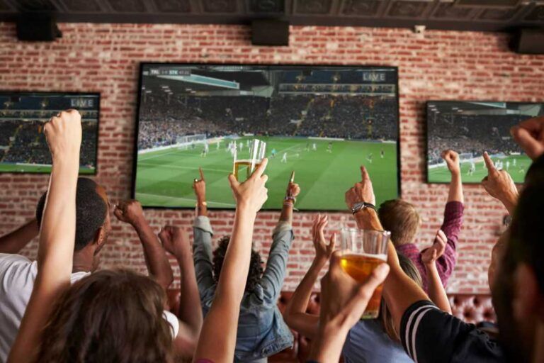 Fãs de futebol assistindo partida nas Olimpíadas em bar da cidade do Porto