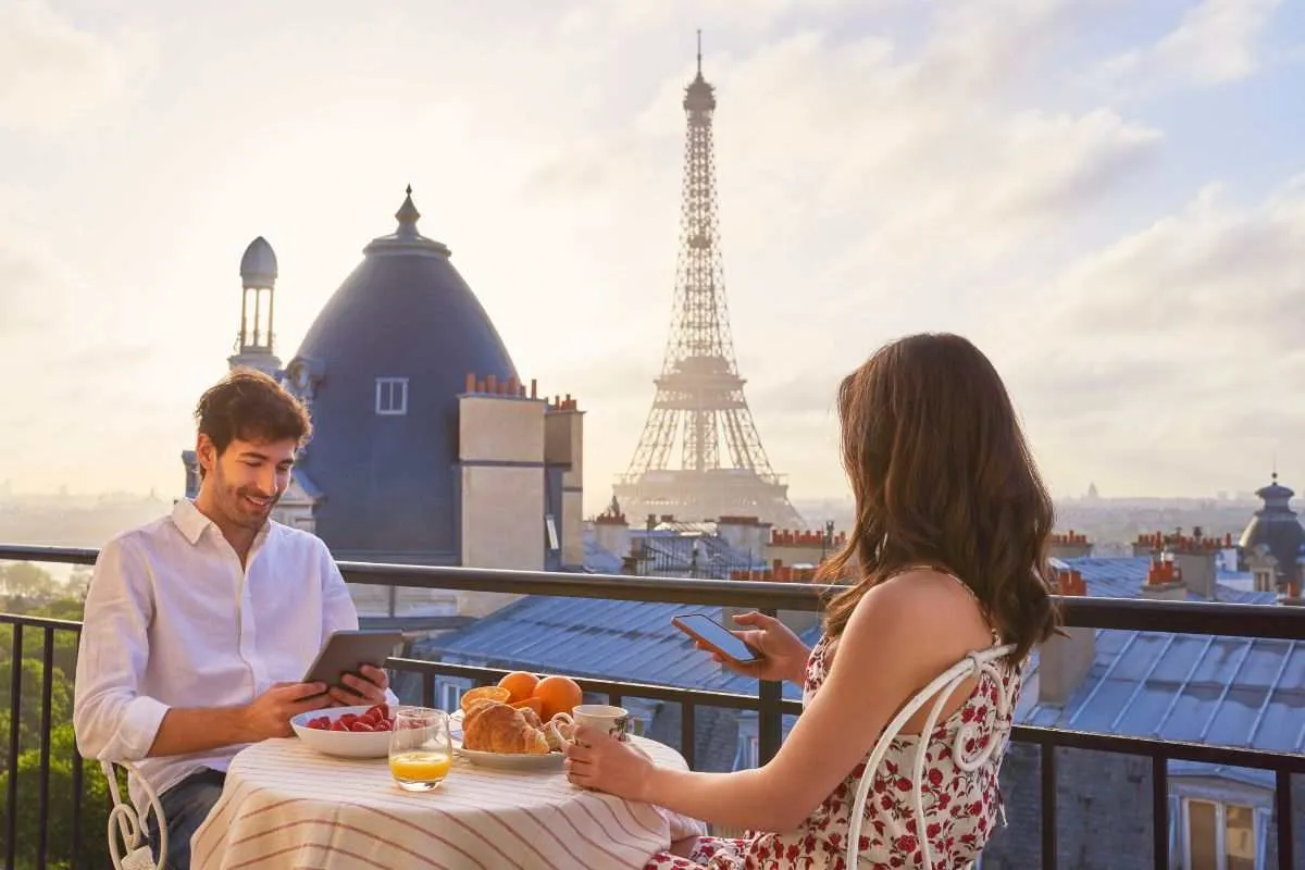 Casal em um restaurante barato em Paris com a Torre Eiffel ao fundo.