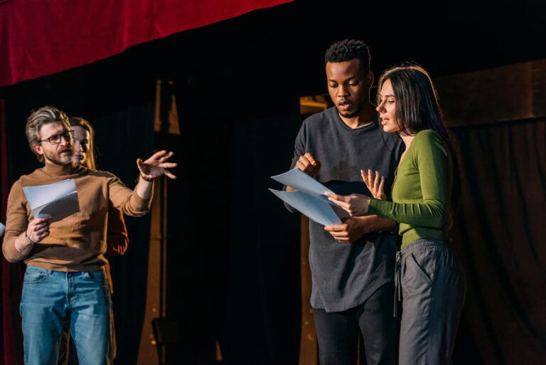 Atores ensaiando uma peça, em um palco de teatro.