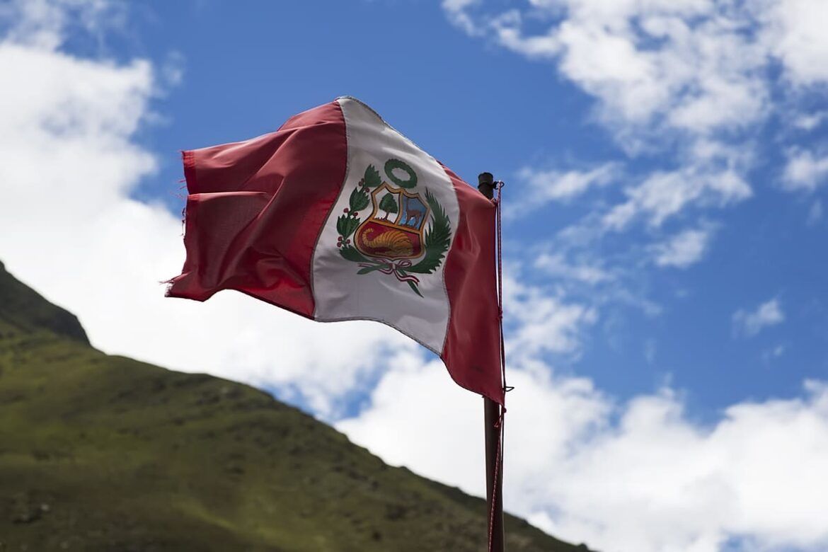 Lima no Peru com a bandeira do país em frente a um campo verde e um céu azul