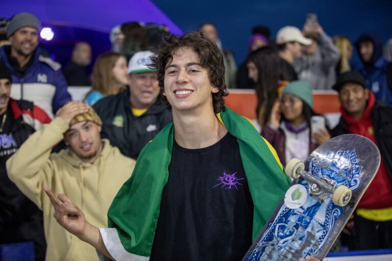 Foto de Luigi Cini segurando seu skate com a bandeira do Brasil nas costas. Reprodução: CBSK