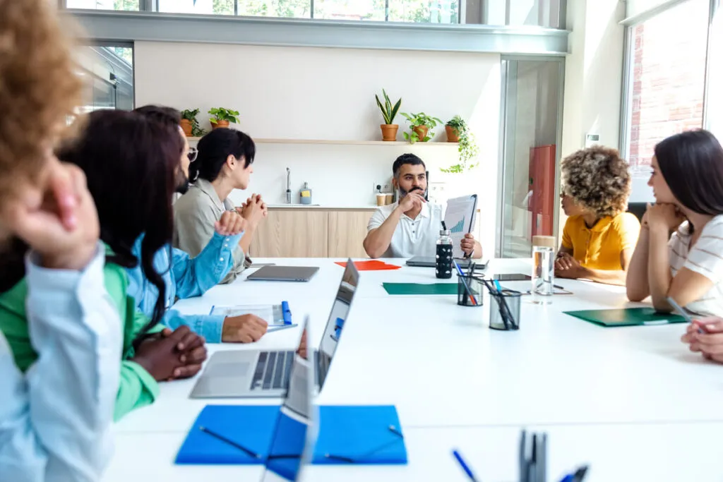 Equipe diversificada de funcionários ouvindo atentamente ao chefe.