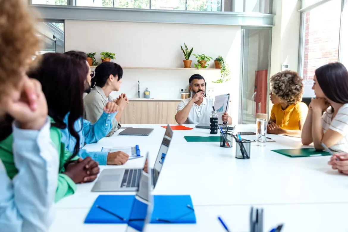 Equipe diversificada de funcionários ouvindo atentamente o chefe.