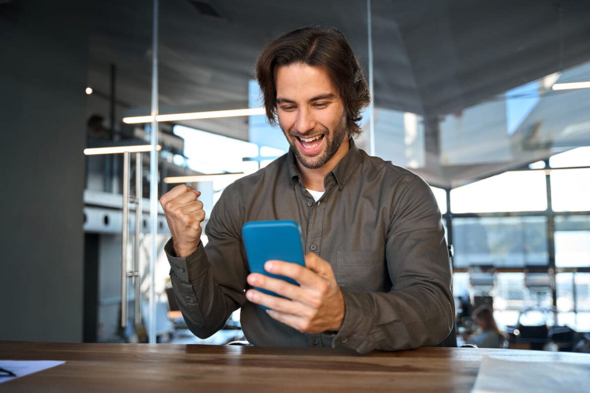 Homem vendo resultados de growth investing na tela do celular e comemorando