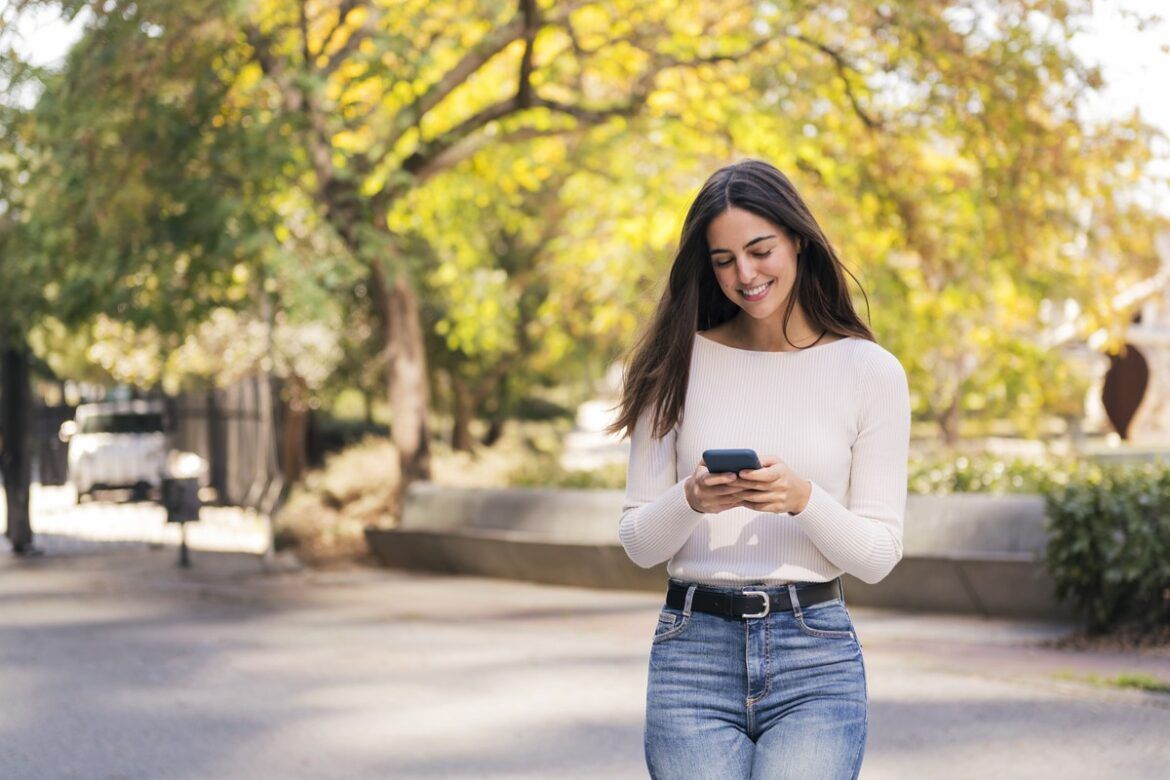 mulher caucasiana sorrindo feliz usando telefone celular